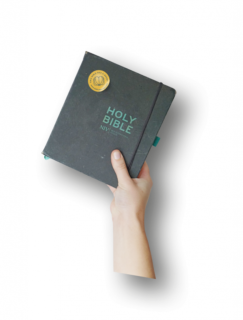 Hand holding up a Bible with the Bible Buddy Sticker on it